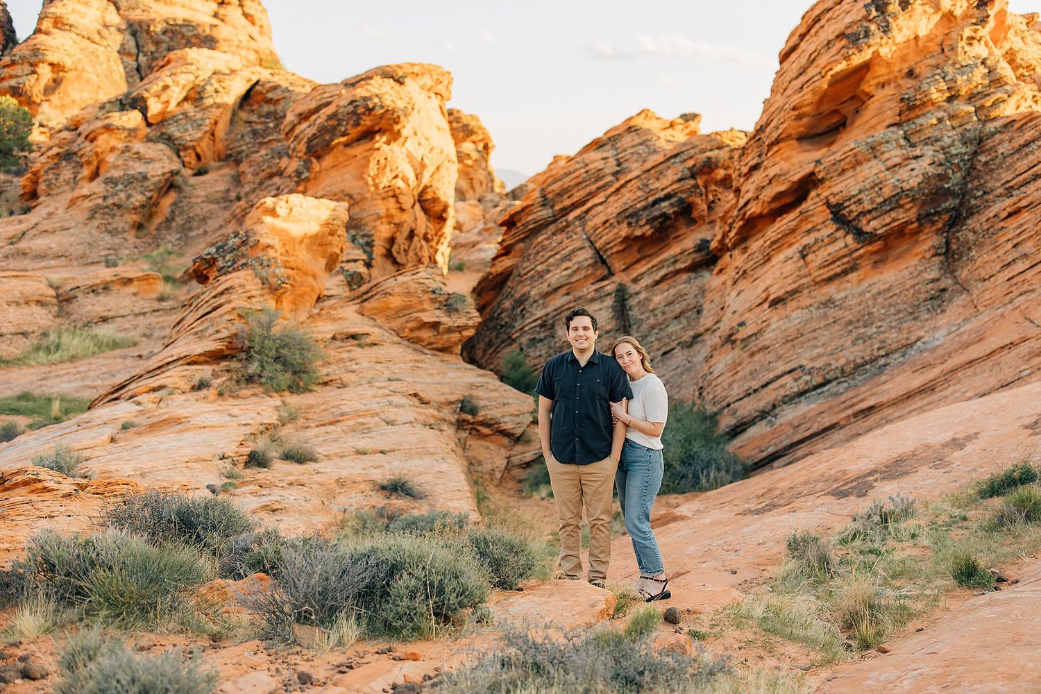 Scenic desert landscape with vibrant orange sandstone formations and desert brush at sunset.