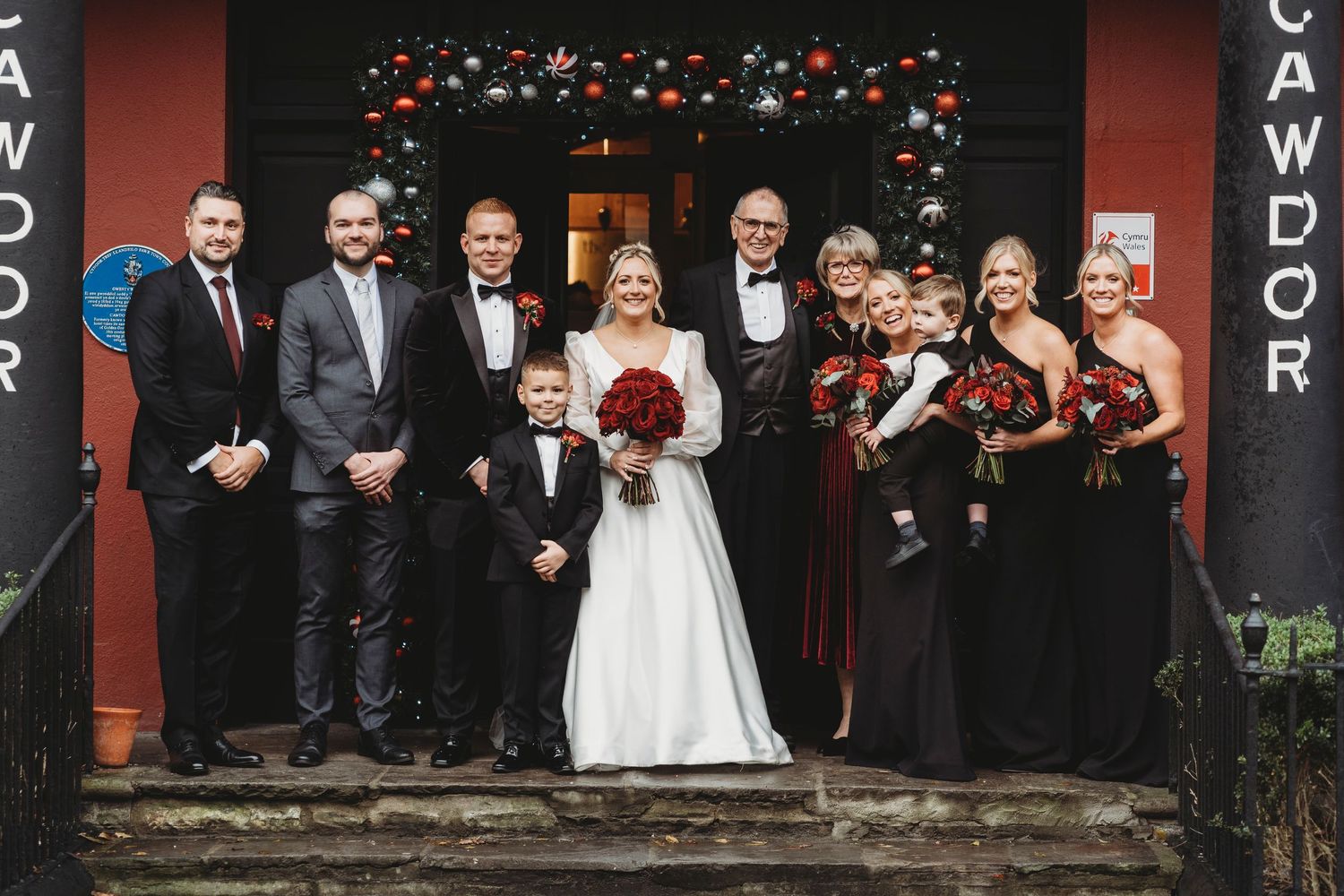 Wedding party and family group photo outside a South Wales wedding venue, with bride and groom surrounded by bridesmaids, groomsmen