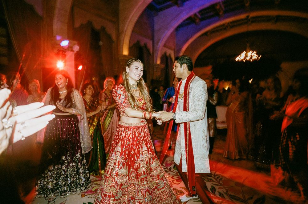 A couple dances together during a wedding reception with red and purple lighting creating a romantic atmosphere.