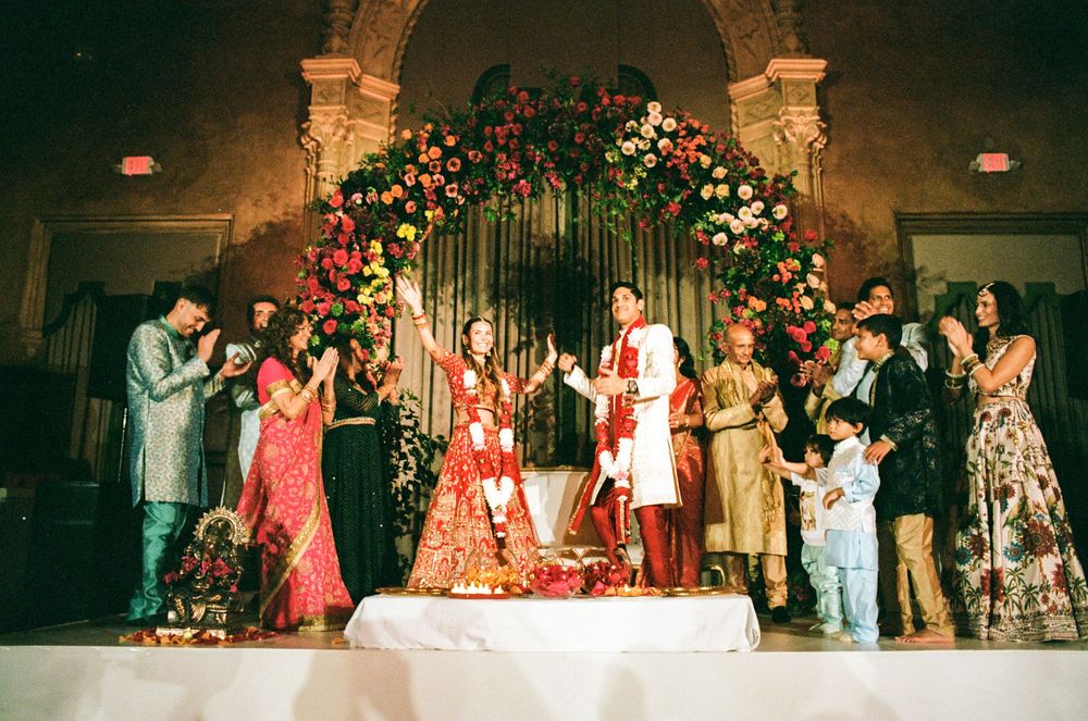 A collage of Indian wedding celebration photos showing traditional ceremonies and festivities in an ornate venue.
