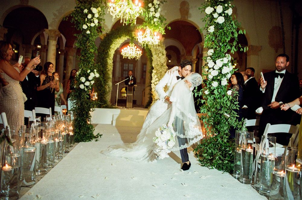 Elegant wedding reception in a grand ballroom decorated with floral arrangements and chandeliers.
