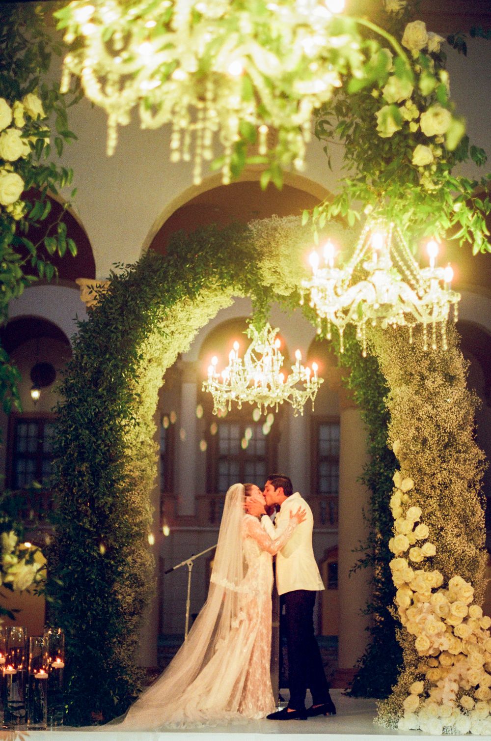 Elegant wedding ceremony setup with floral arches, crystal chandeliers and soft lighting creating a romantic ambiance.