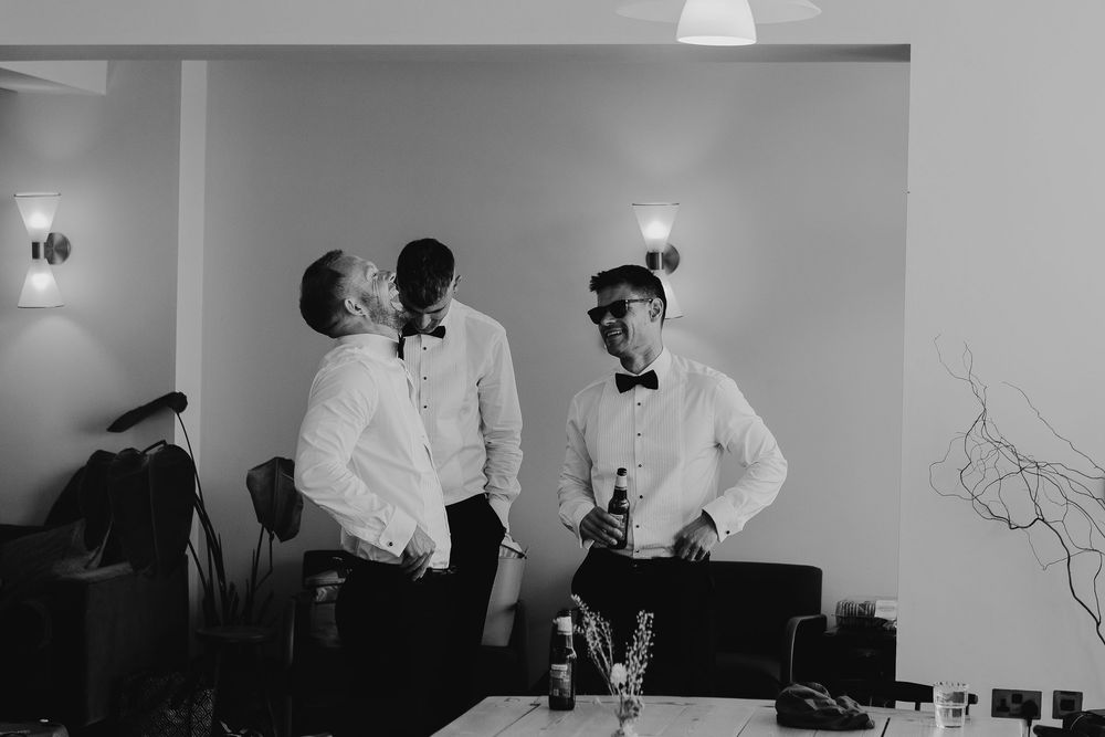 Wedding party getting ready in minimalist white room with natural lighting.