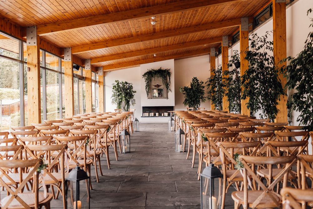 Reception hall with wooden ceiling and cross-back chairs arranged in neat rows for wedding ceremony.