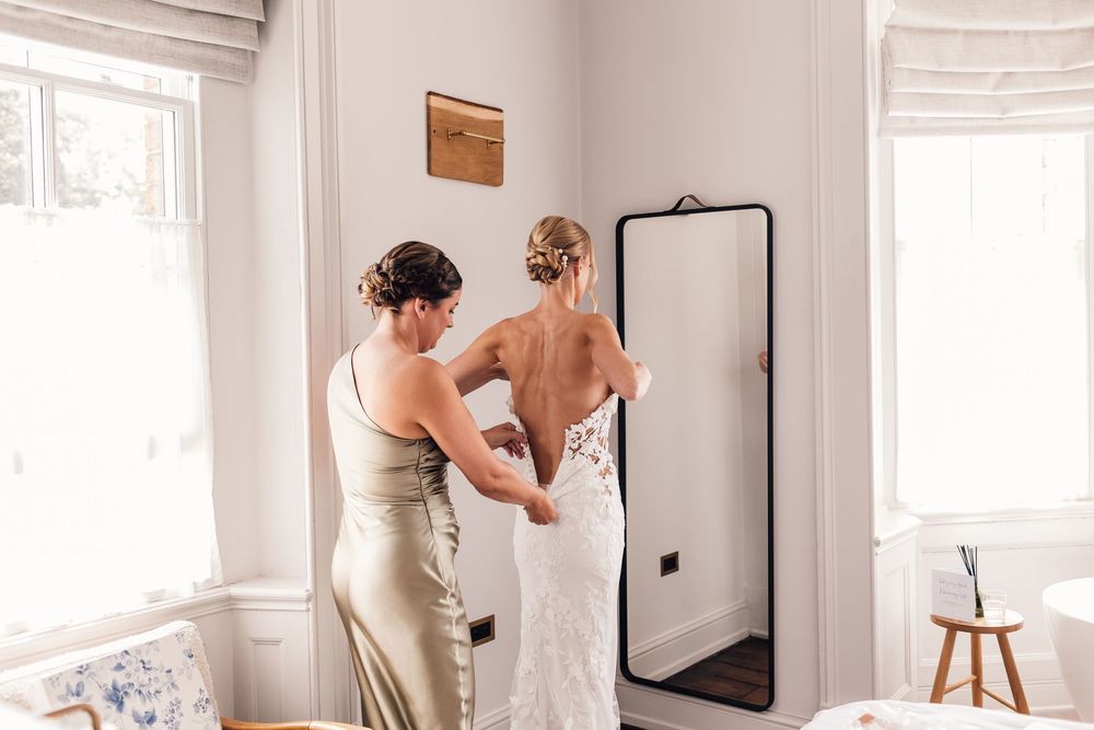 Light-filled bridal preparation room with white decor and getting ready moments captured in mirror reflections.