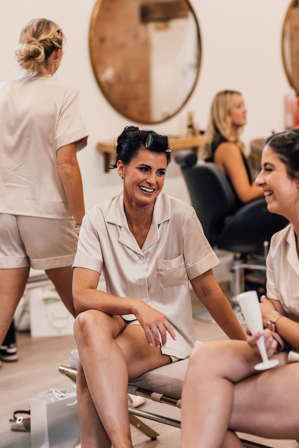 Wedding party members in white outfits gather in a casual indoor setting with modern decor.
