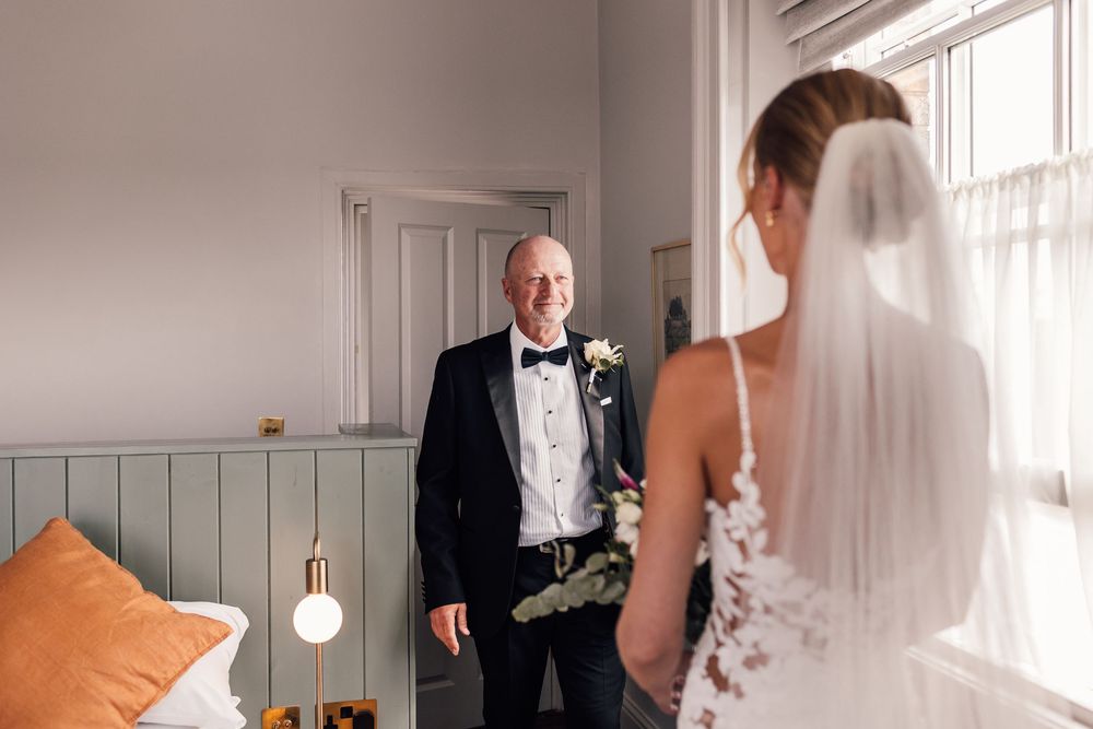 Elegant wedding preparation scene in bright white room with natural window light.