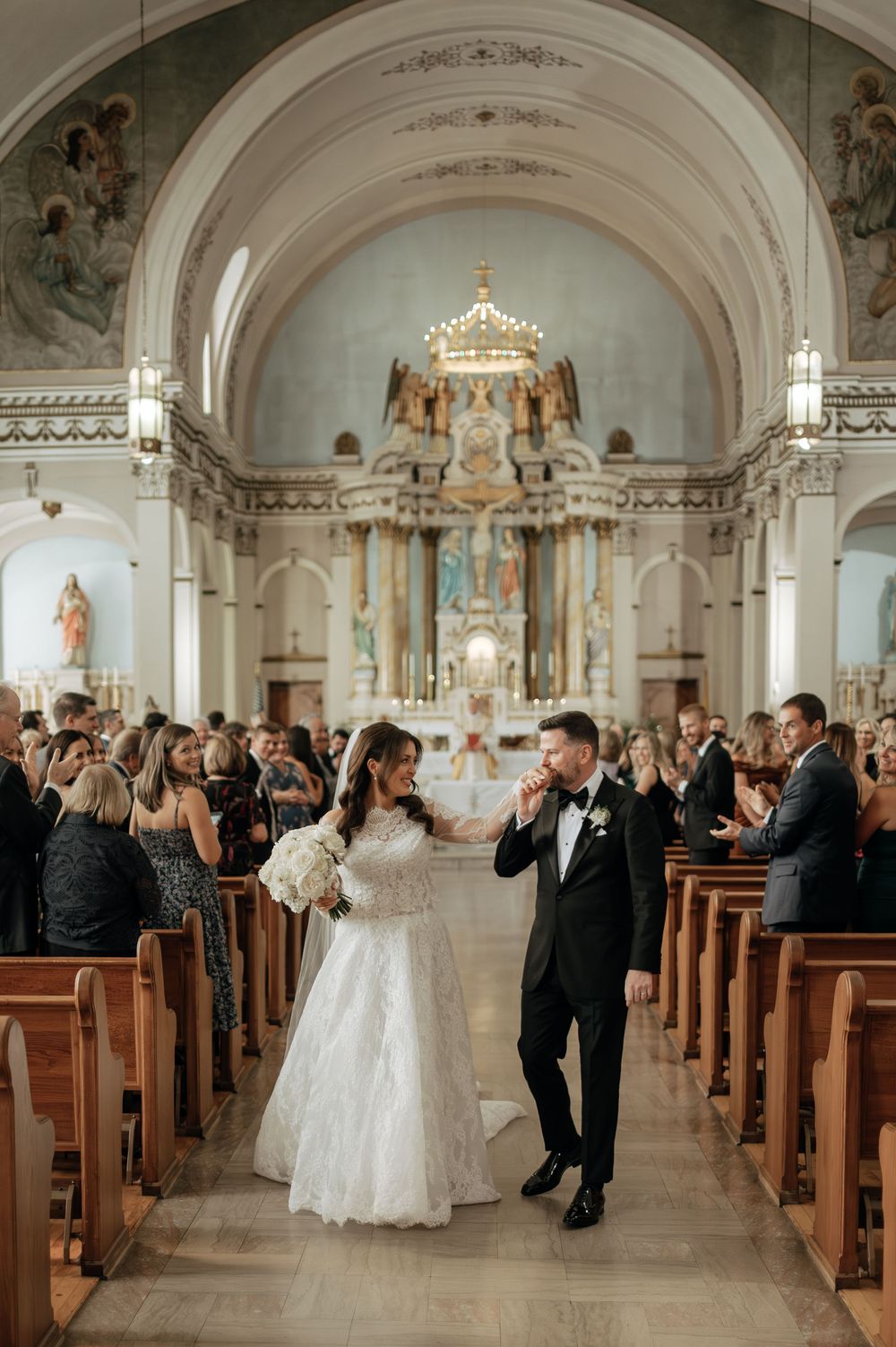 Bride and groom walk down the aisle after their wedding ceremony in a beautiful ornate church.