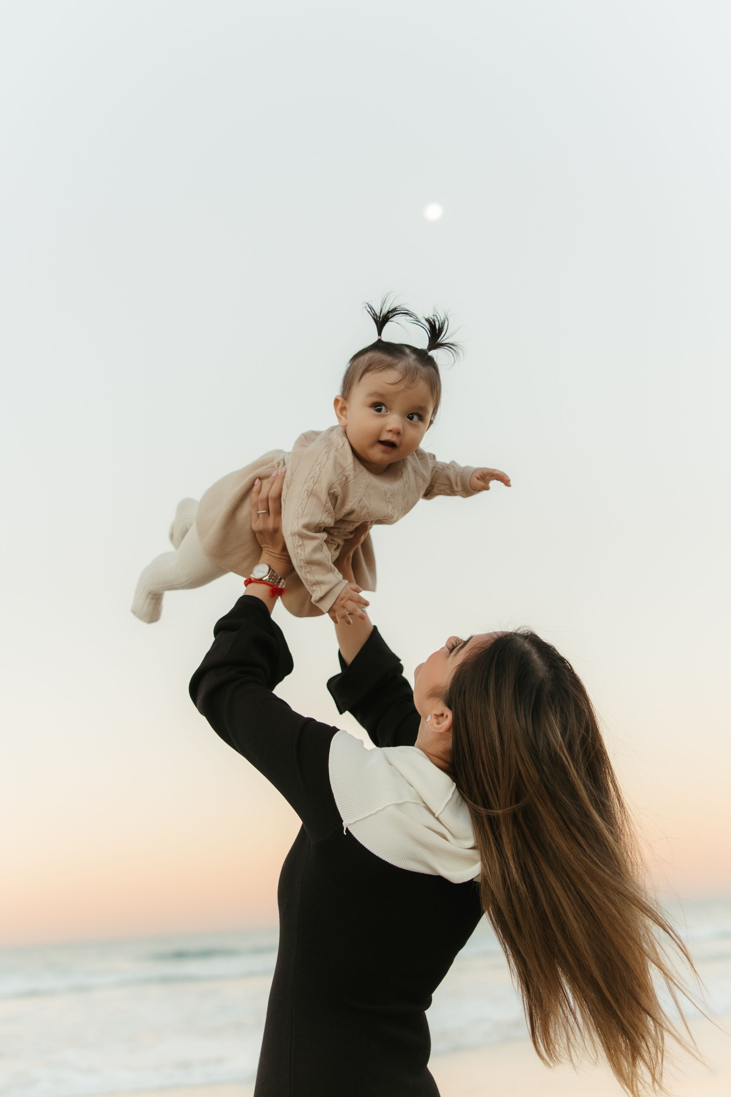 A parent lifts and plays with a small child against a sunset sky backdrop in a series of joyful moments.