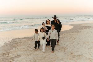 Family enjoying a sunset walk together along a peaceful beach shoreline.