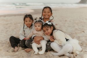 Group relaxing together on beach sand while wearing coordinated white outfits.