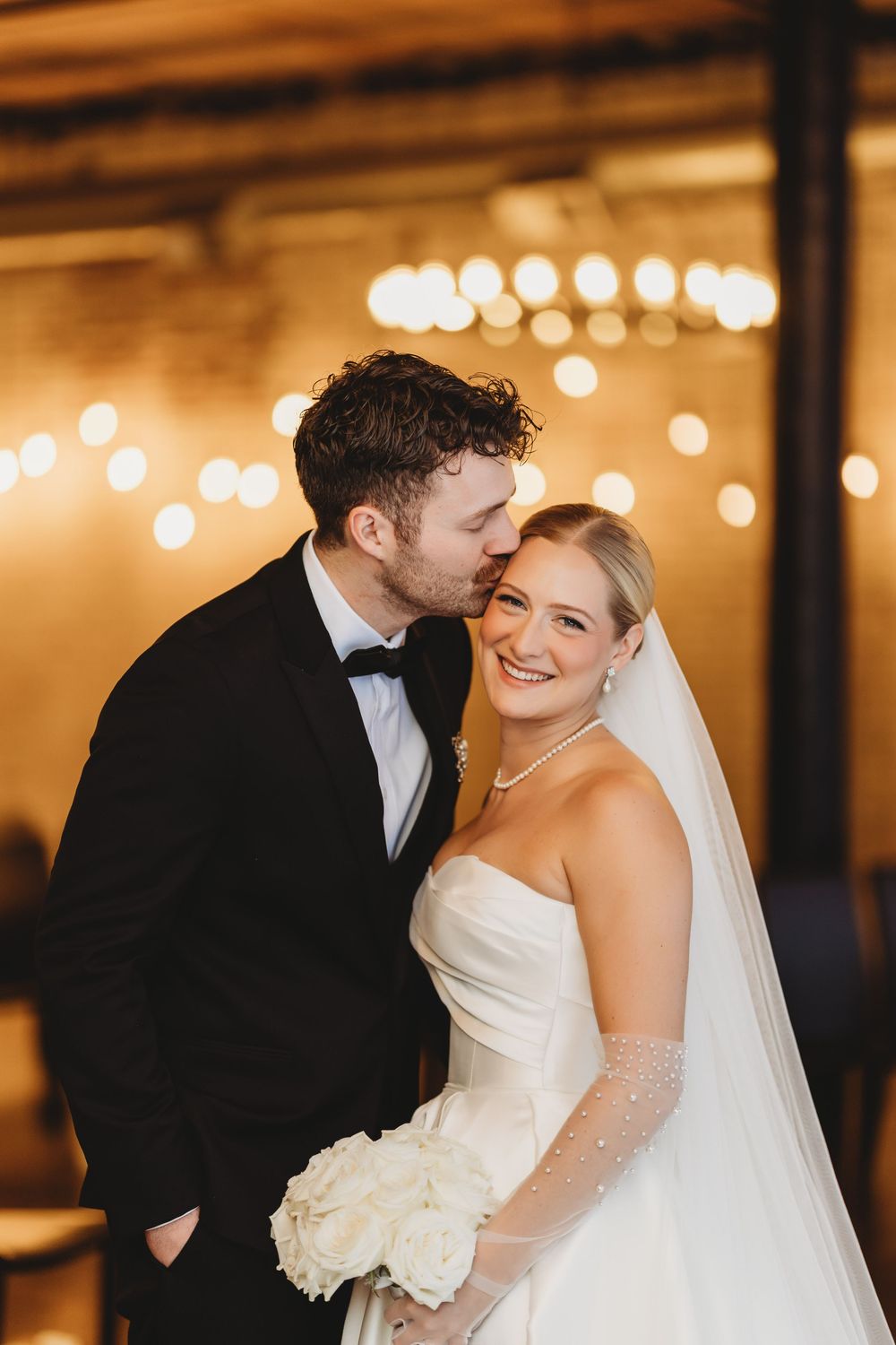 Romantic wedding couple sharing intimate moments under warm glowing lights at their reception.