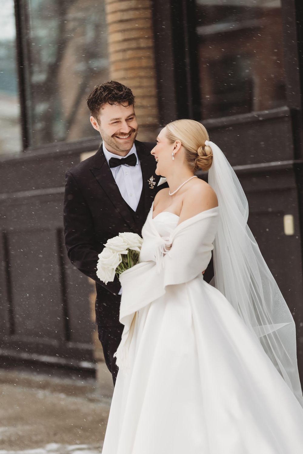 Winter wedding couple sharing joyful moments in their formal attire outside.