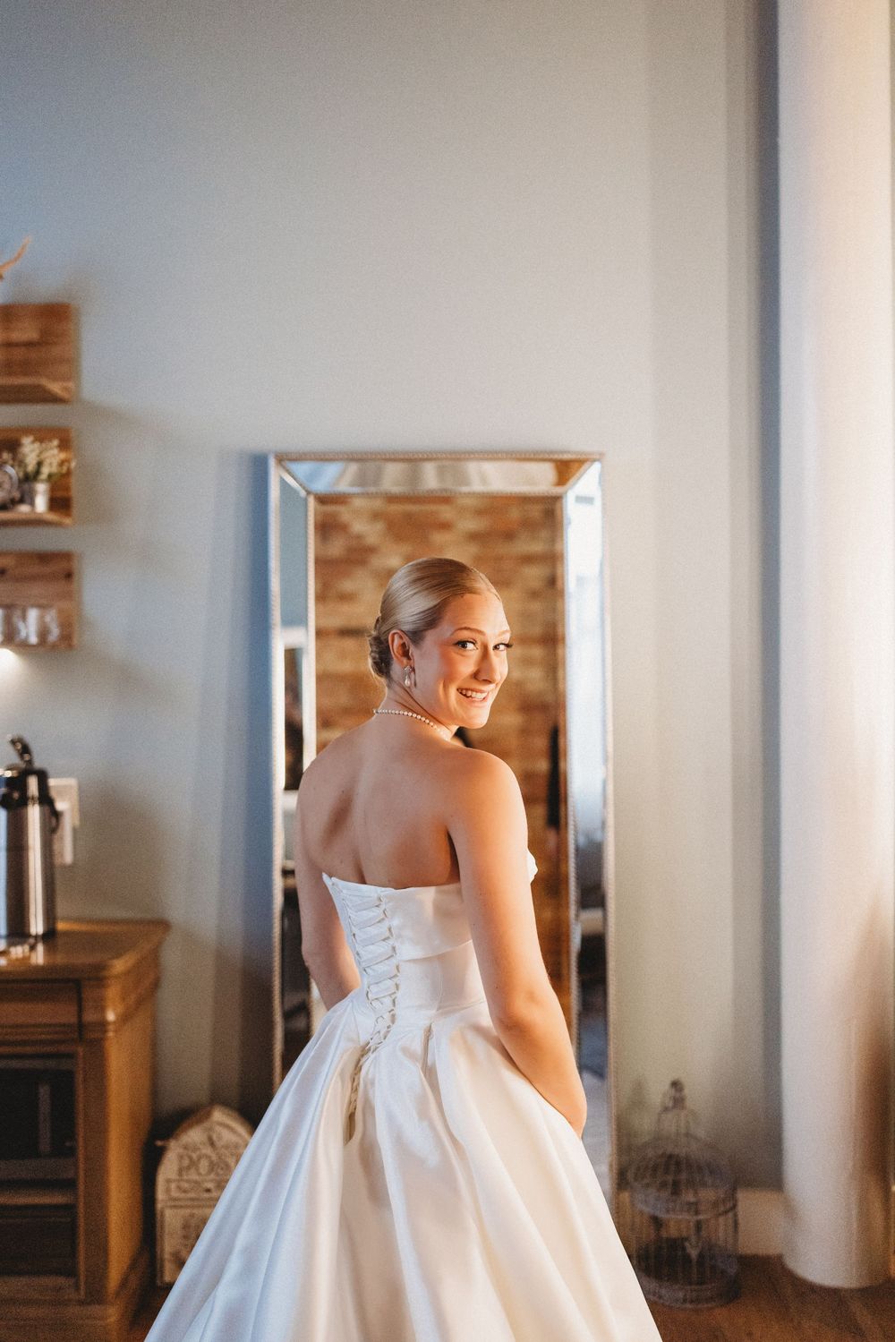 Bride in elegant white dress smiles while getting ready.