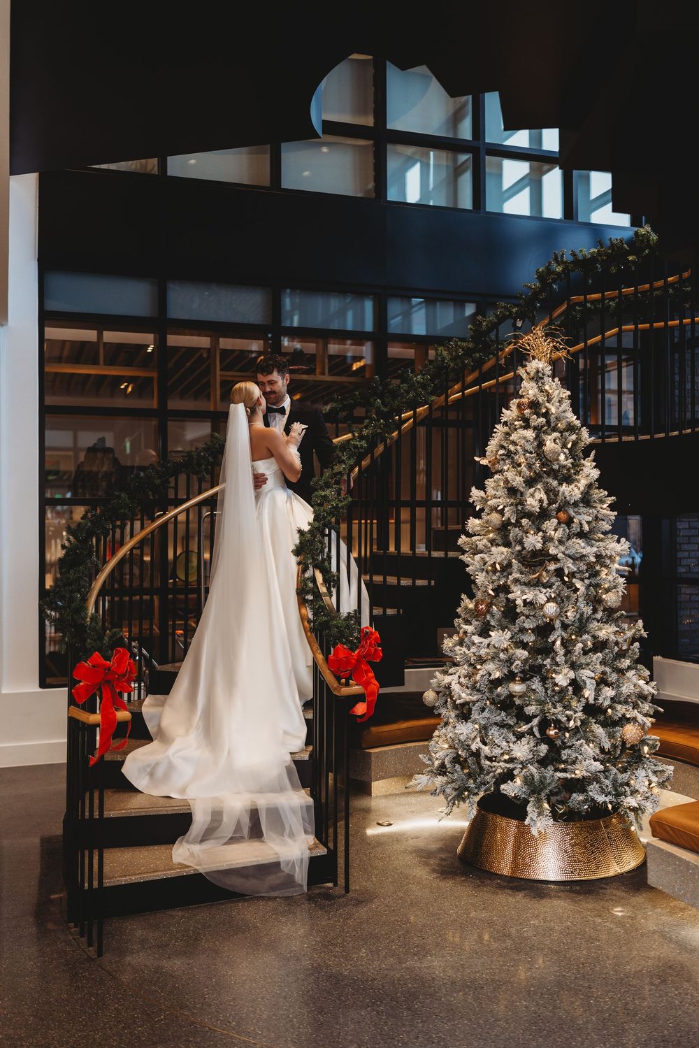 Elegant white wedding dress displayed next to a decorated Christmas tree with twinkling lights and holiday decor.