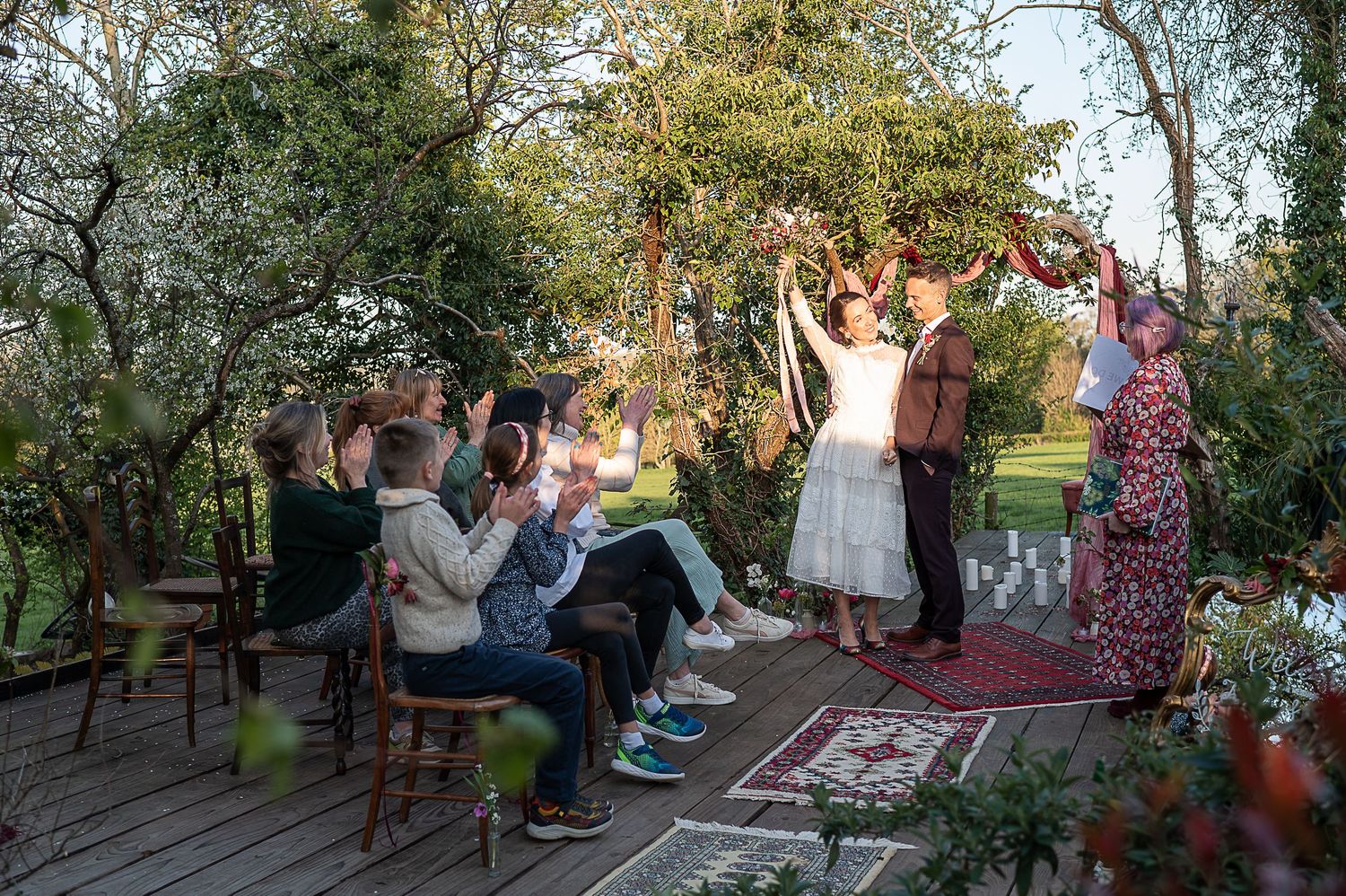 Newlywed couple celebrate on the decking at Nature's Edge Cabin. Their guests and celebrant cheer.