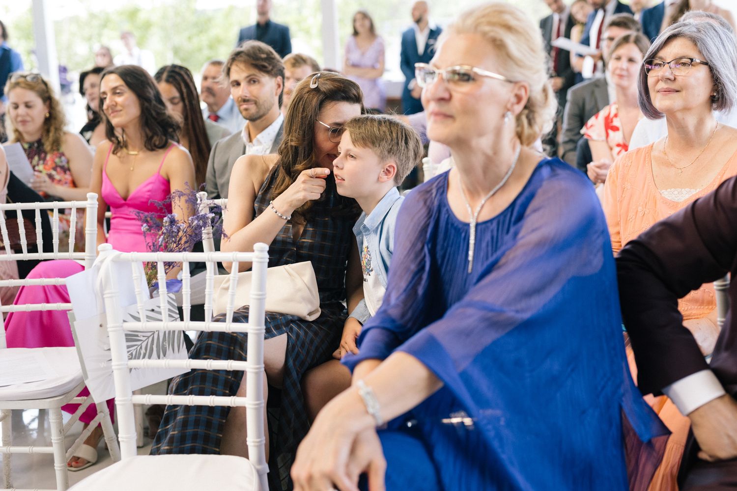 Wedding guests and family members seated in rows during an indoor ceremony.