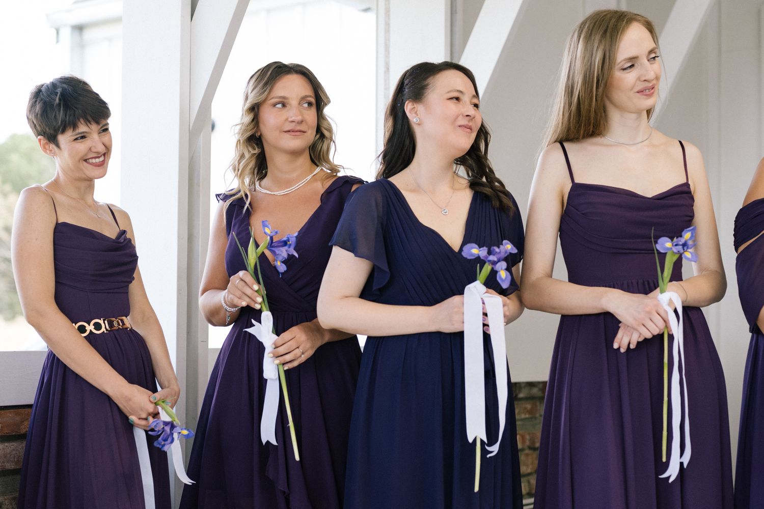 Bridesmaids wearing coordinated purple dresses pose together during wedding festivities.