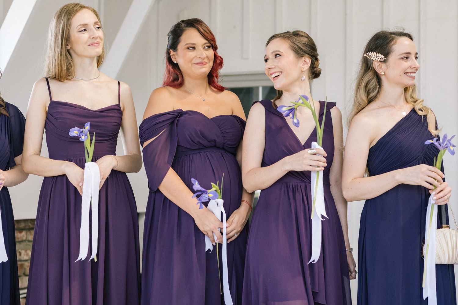 Bridesmaids in elegant purple dresses stand together at a formal wedding ceremony.