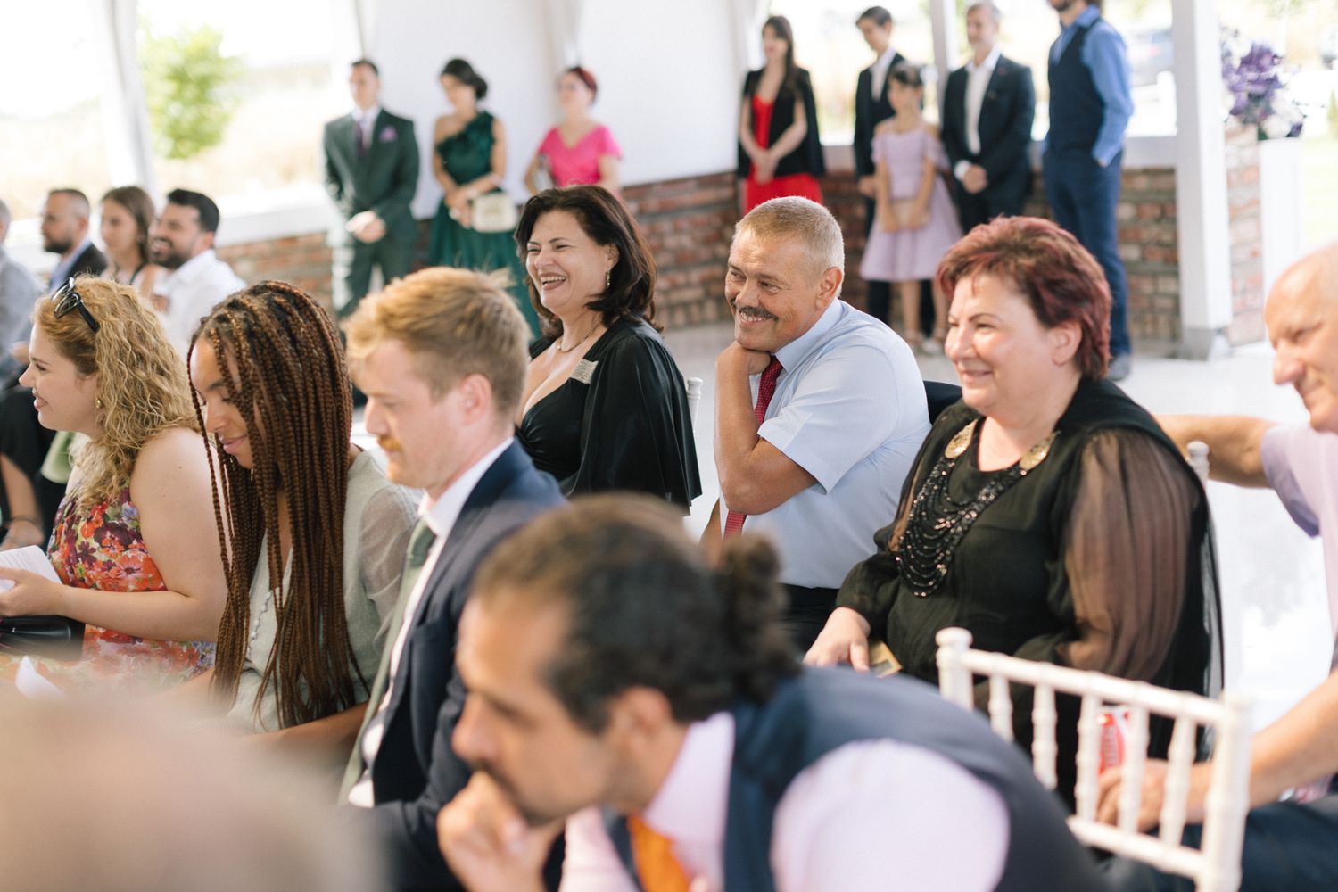 Wedding guests seated in rows during an indoor ceremony with natural lighting.