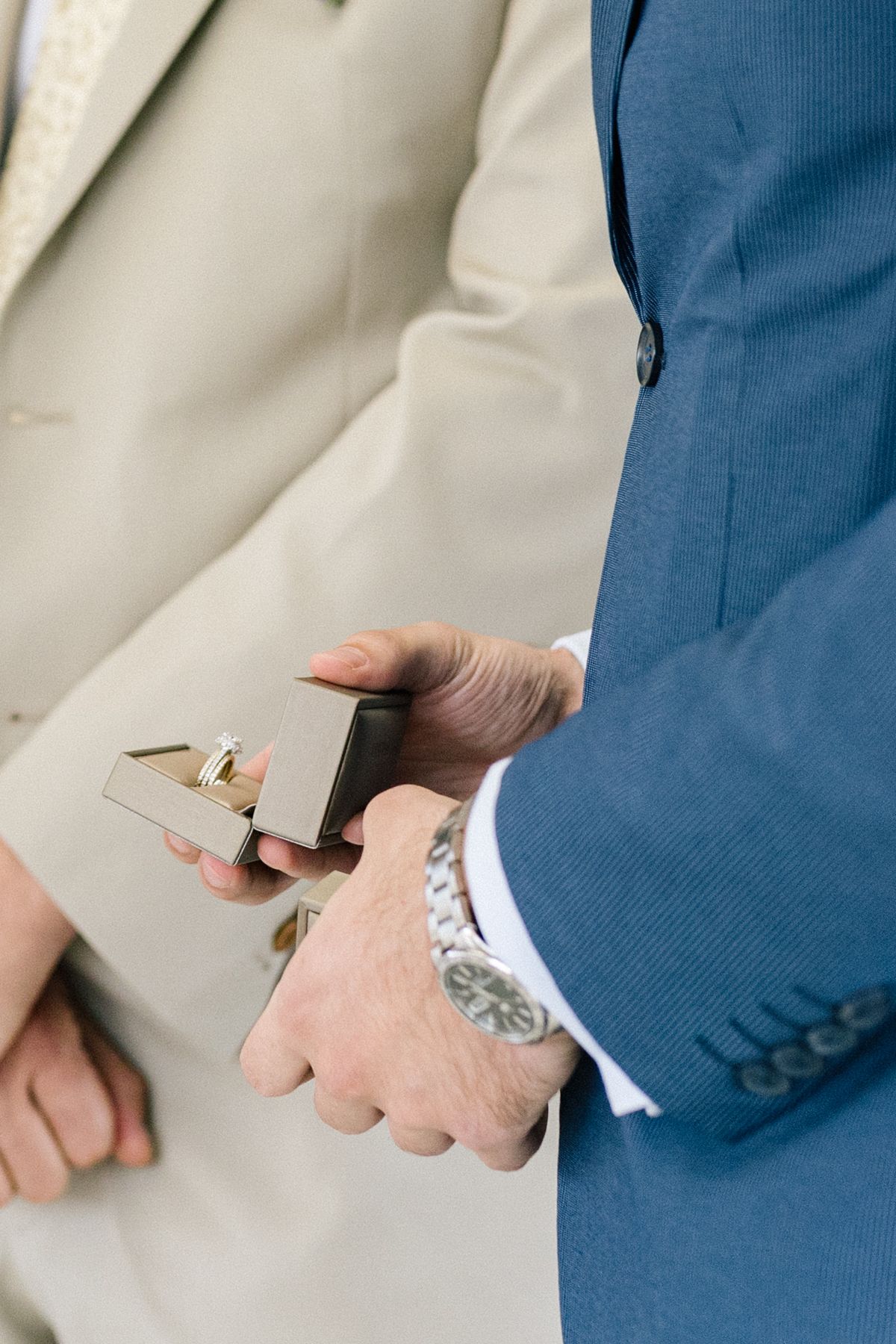Close-up details of formal attire and hands during a wedding ceremony.