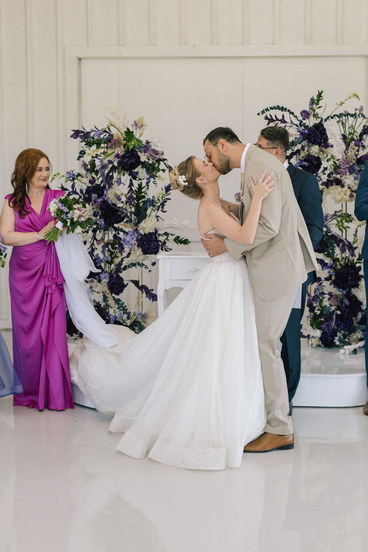 Wedding party in white and purple attire performing ceremonial dances in an elegant venue.