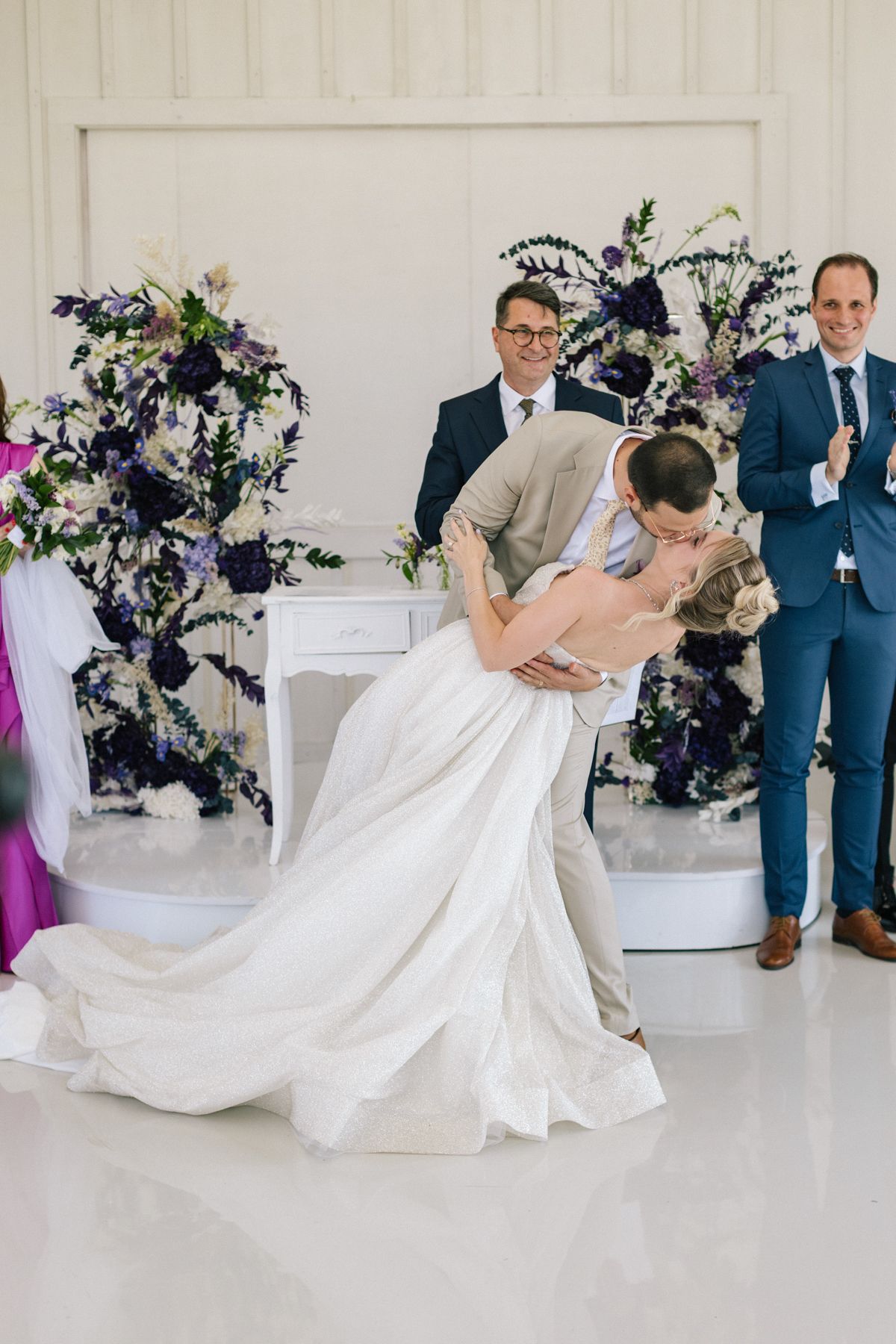 Wedding celebration with dramatic dips and dance moves in a white decorated venue.