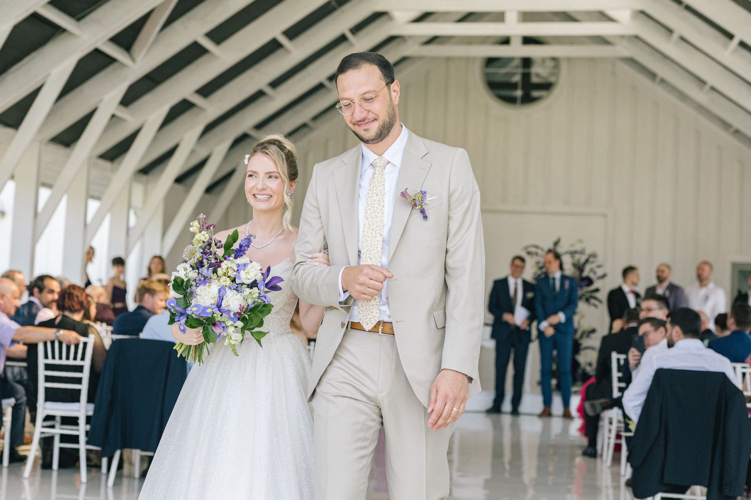 Newlyweds dancing in a spacious reception hall with vaulted ceilings and white decor.