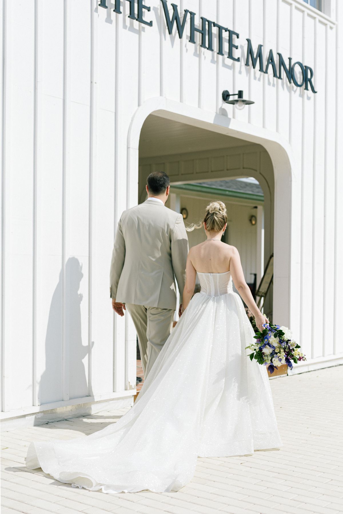 Wedding couple walks outside The White Manor building entrance.