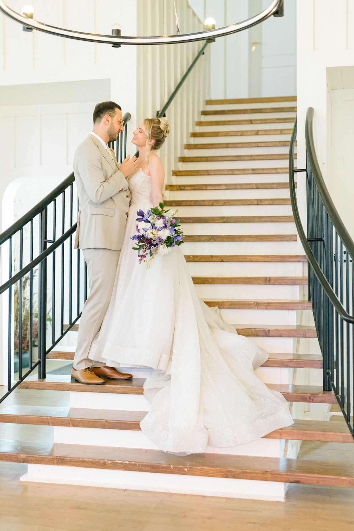 First look wedding moment captured on an elegant staircase with natural lighting.
