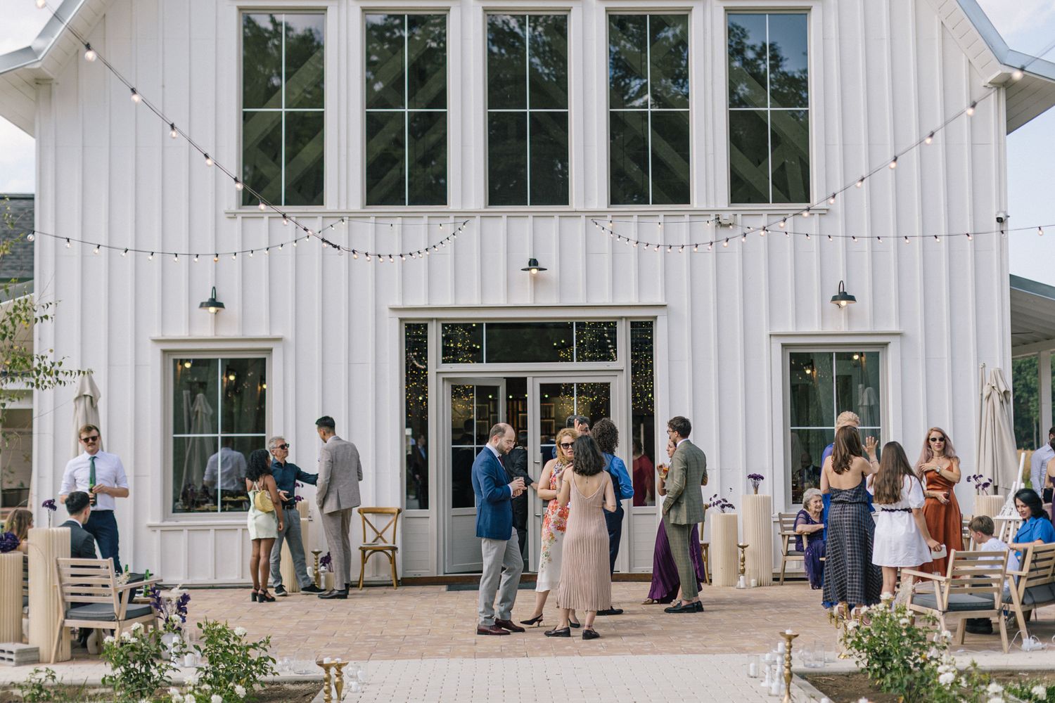 Modern white barn wedding venue exterior features large windows and clean architectural lines.