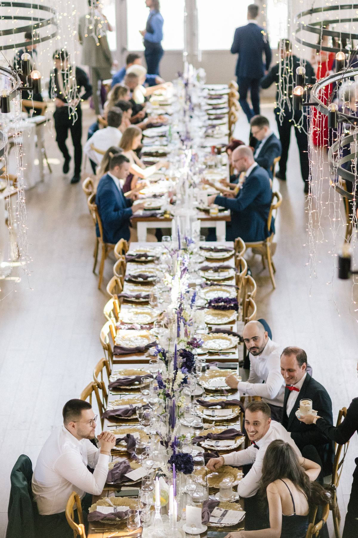 Long dining table set for wedding reception with crystal decorations and gold chairs.