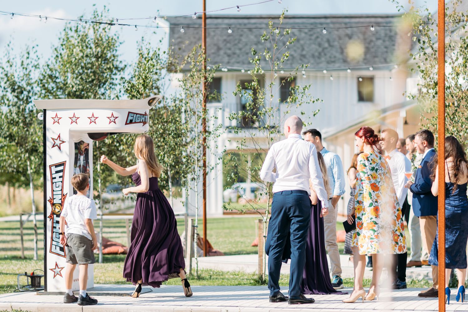 Wedding guests gather outdoors under string lights during evening celebration.
