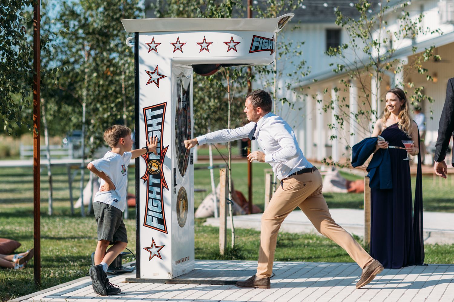 Children play on outdoor game stations during wedding reception.