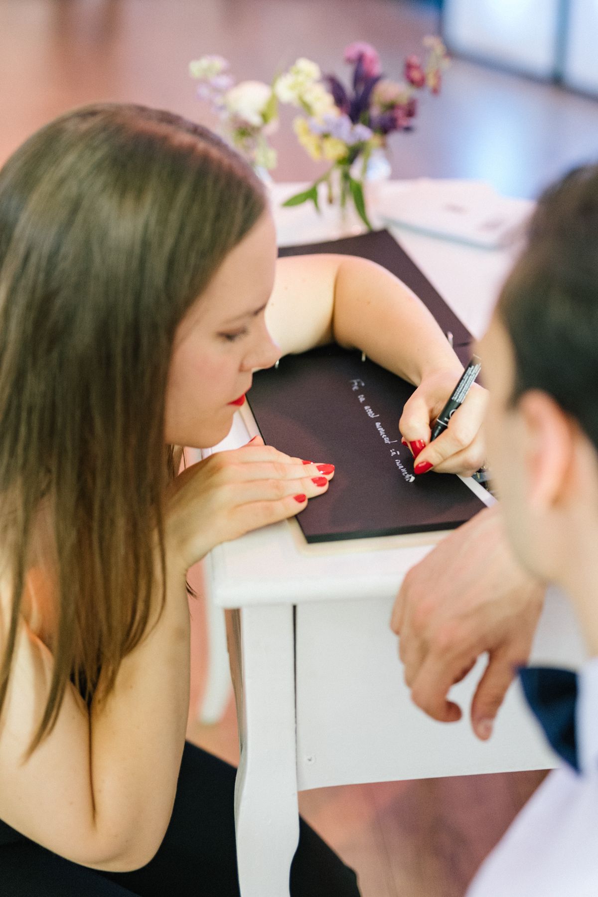 Guest signing the wedding guestbook at an elegant reception.