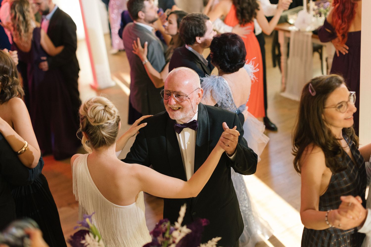 Couples dancing at an elegant wedding reception with formal attire and romantic lighting.