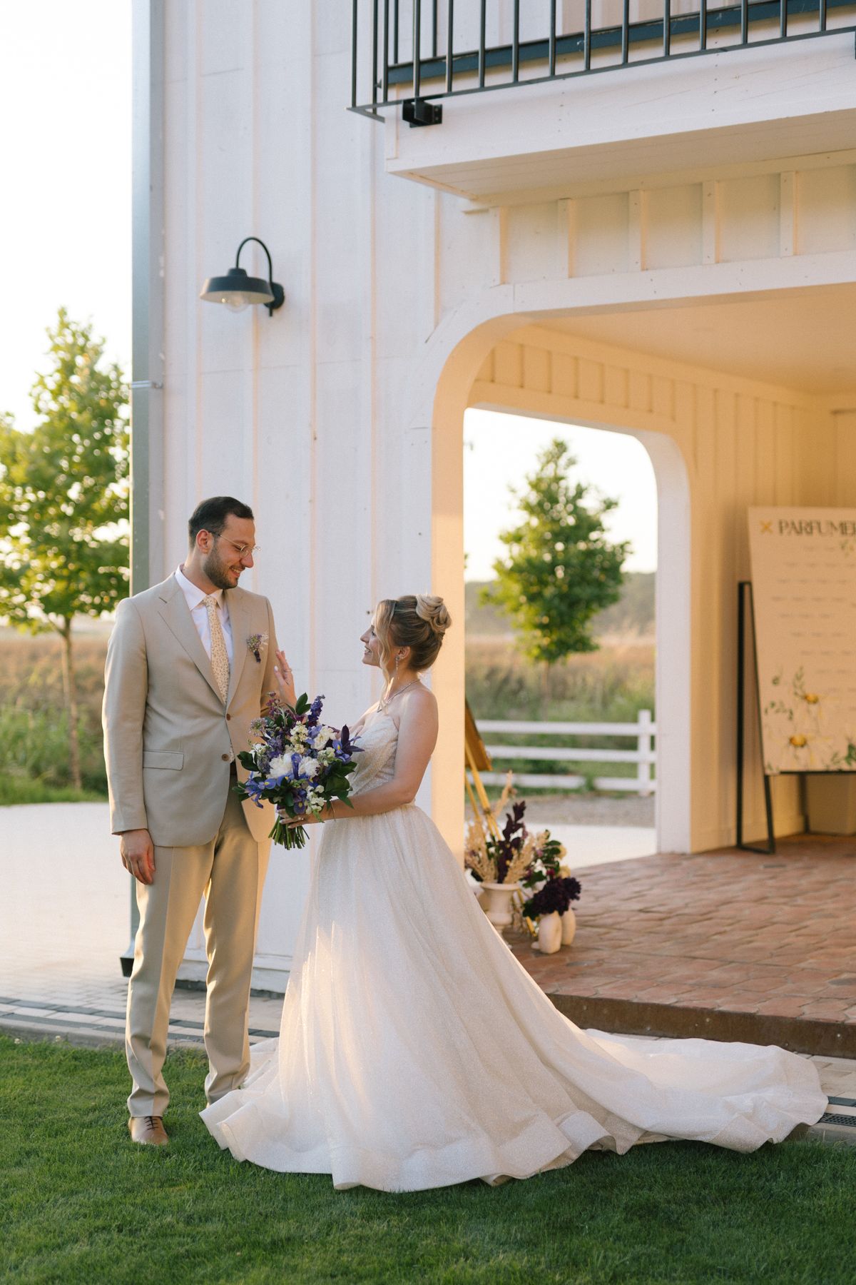 Bride and groom sharing romantic moments on a white columned porch at sunset.