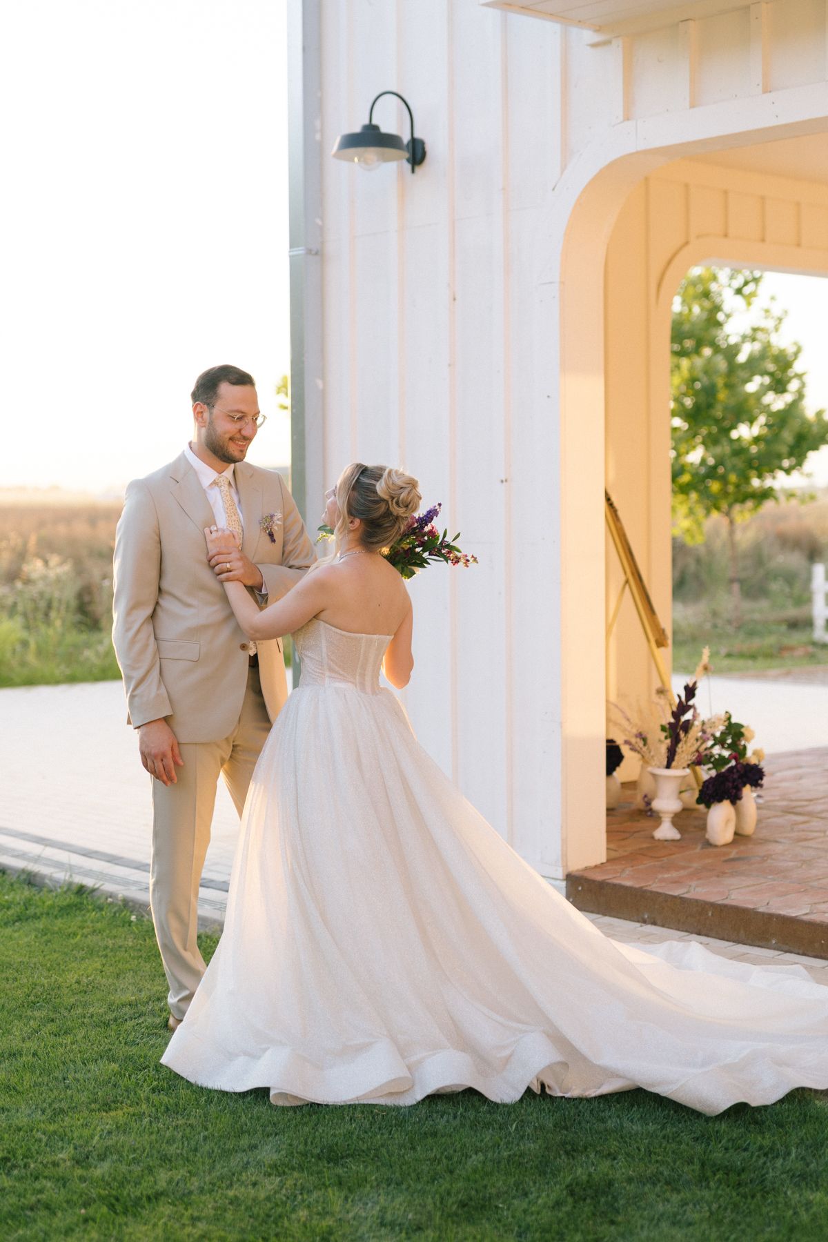 Wedding couple dancing together on a white porch during golden hour sunset.