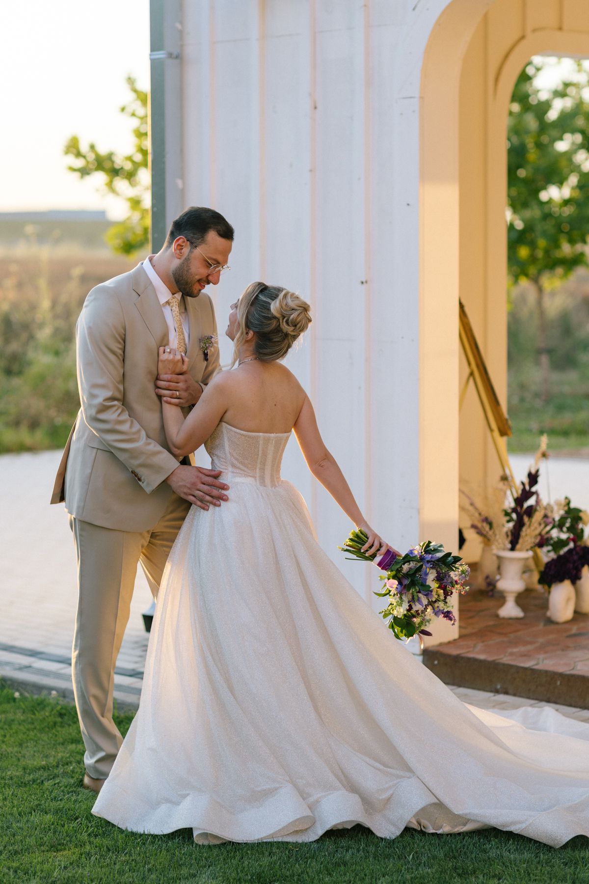 Elegant couple dancing together on a white porch with bride's dress flowing beautifully.
