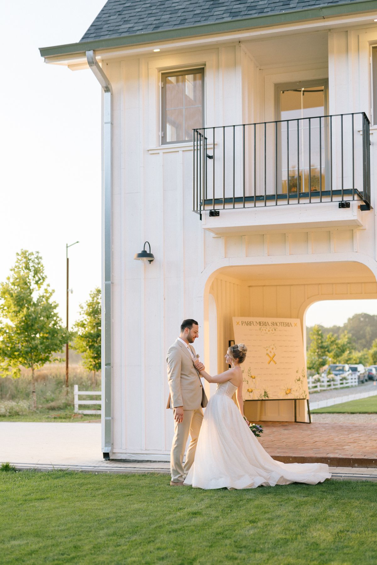 Wedding photography session outside a white farmhouse style building with green roof.
