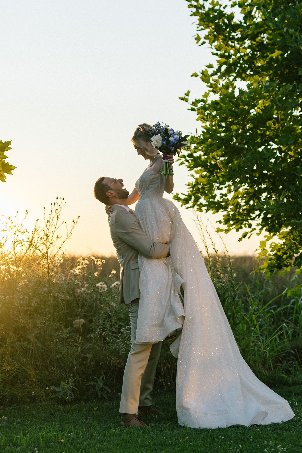 Joyful wedding couple shares intimate dance moves outdoors during sunset.