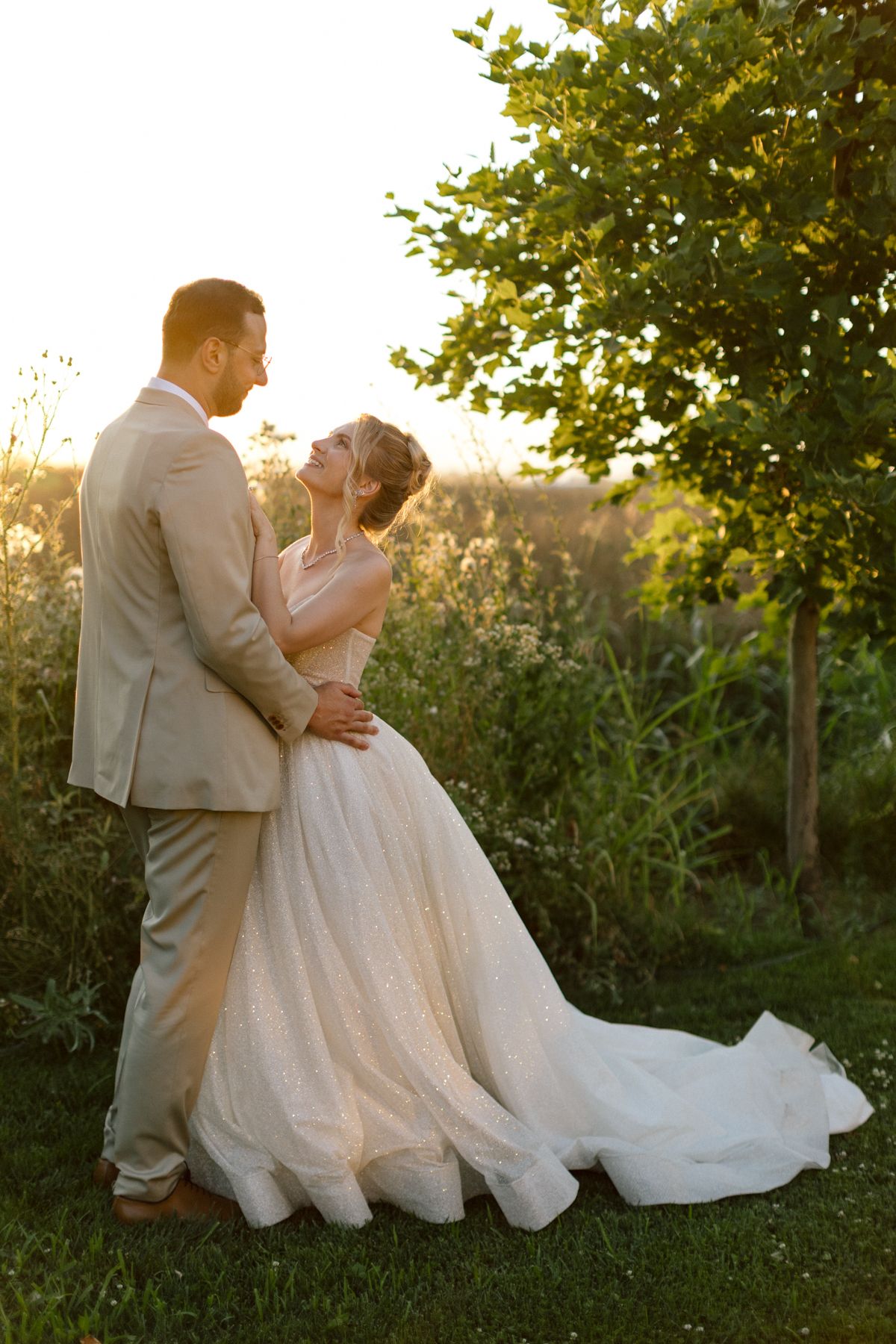 A romantic wedding couple embraces in a garden setting during golden hour.