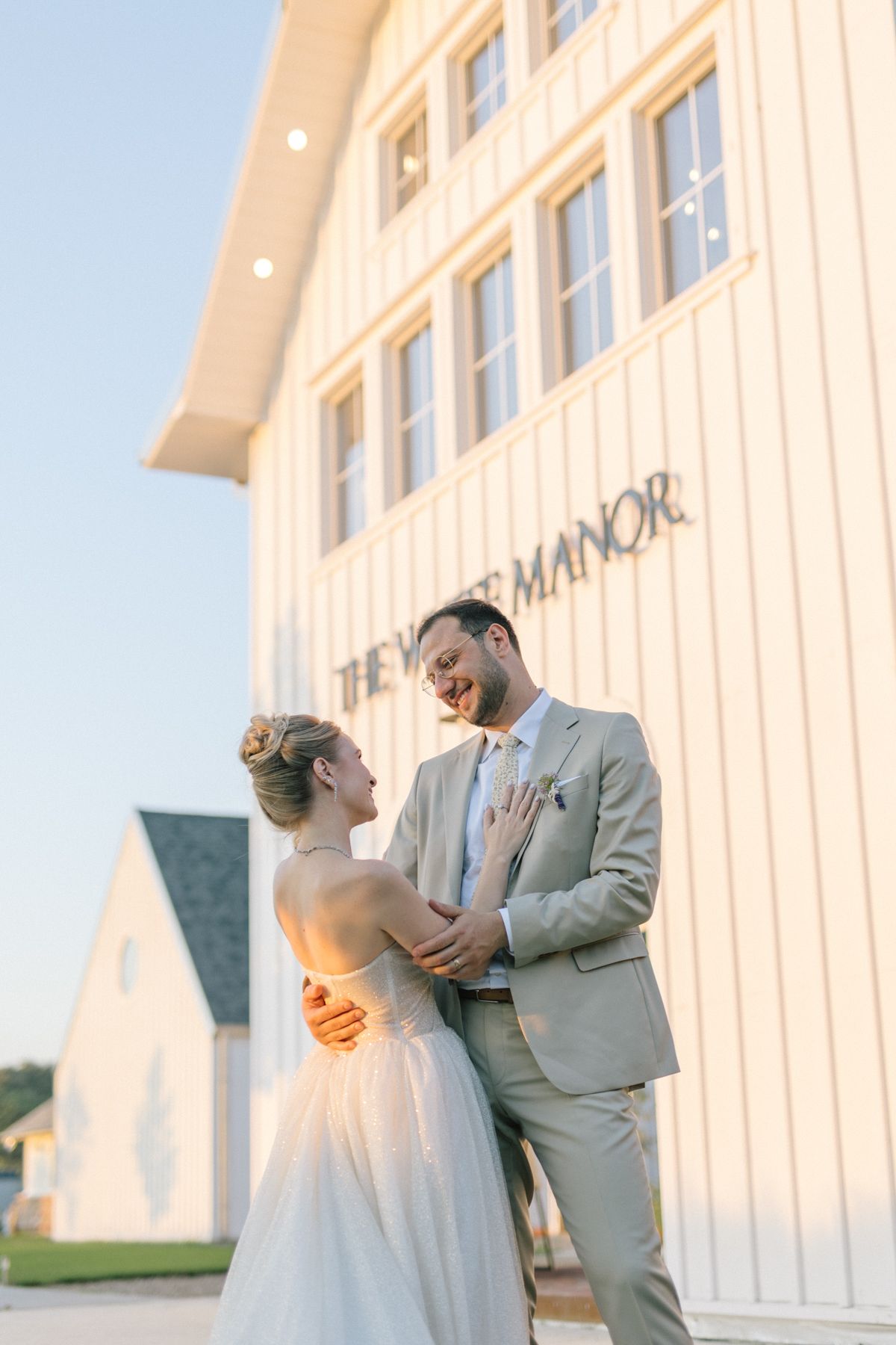 A tender moment between newlyweds against a white manor backdrop.