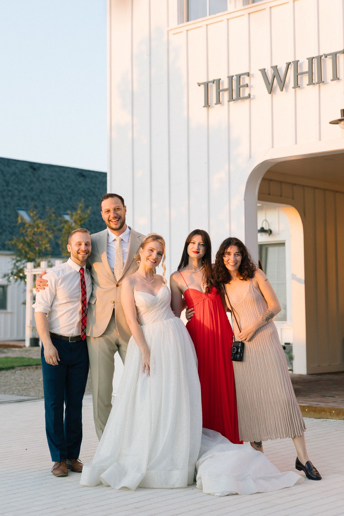 Large wedding party in coordinated formal attire poses at The White Manor venue.