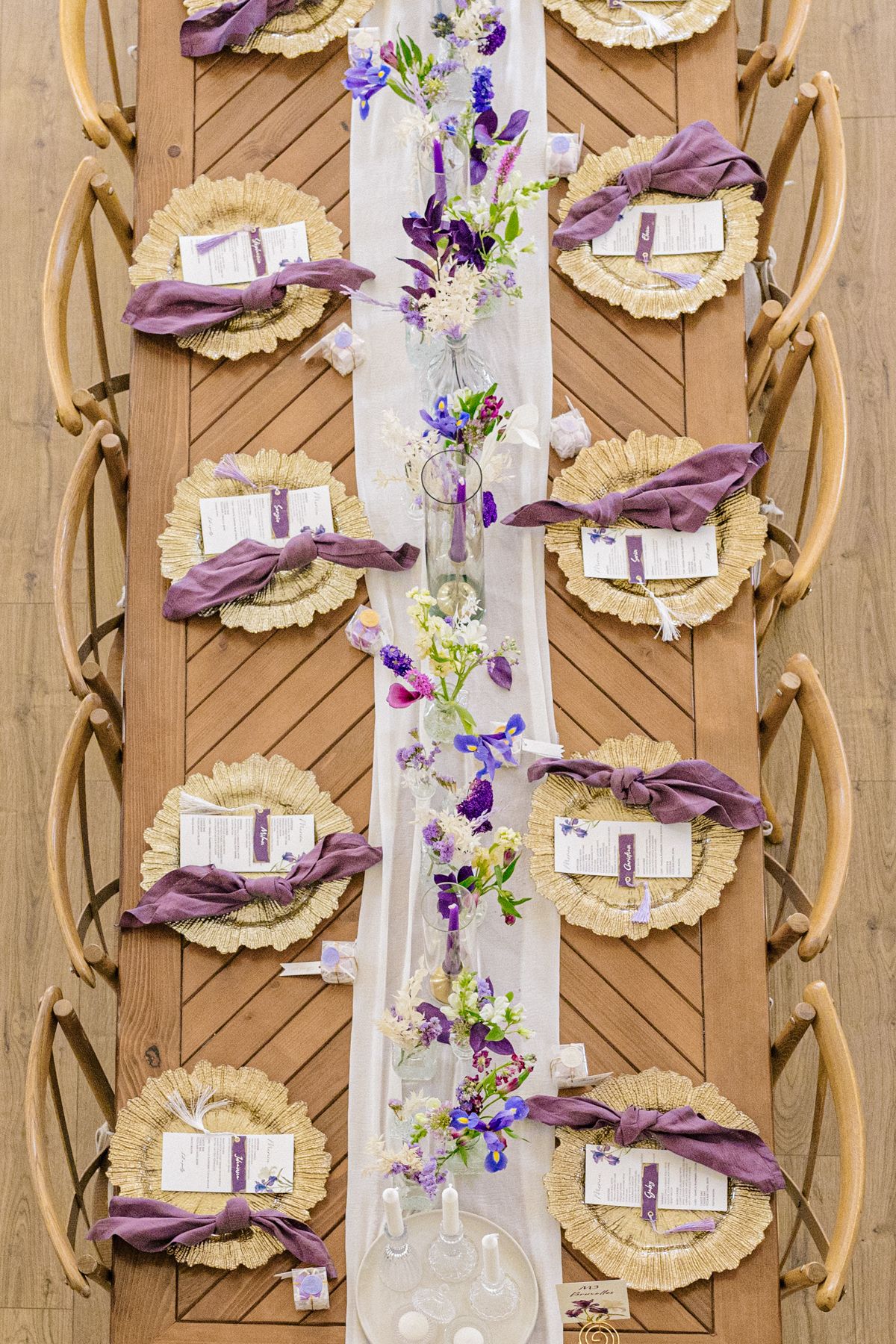 Overhead view of place settings with gold chargers and purple napkins arranged in a row.
