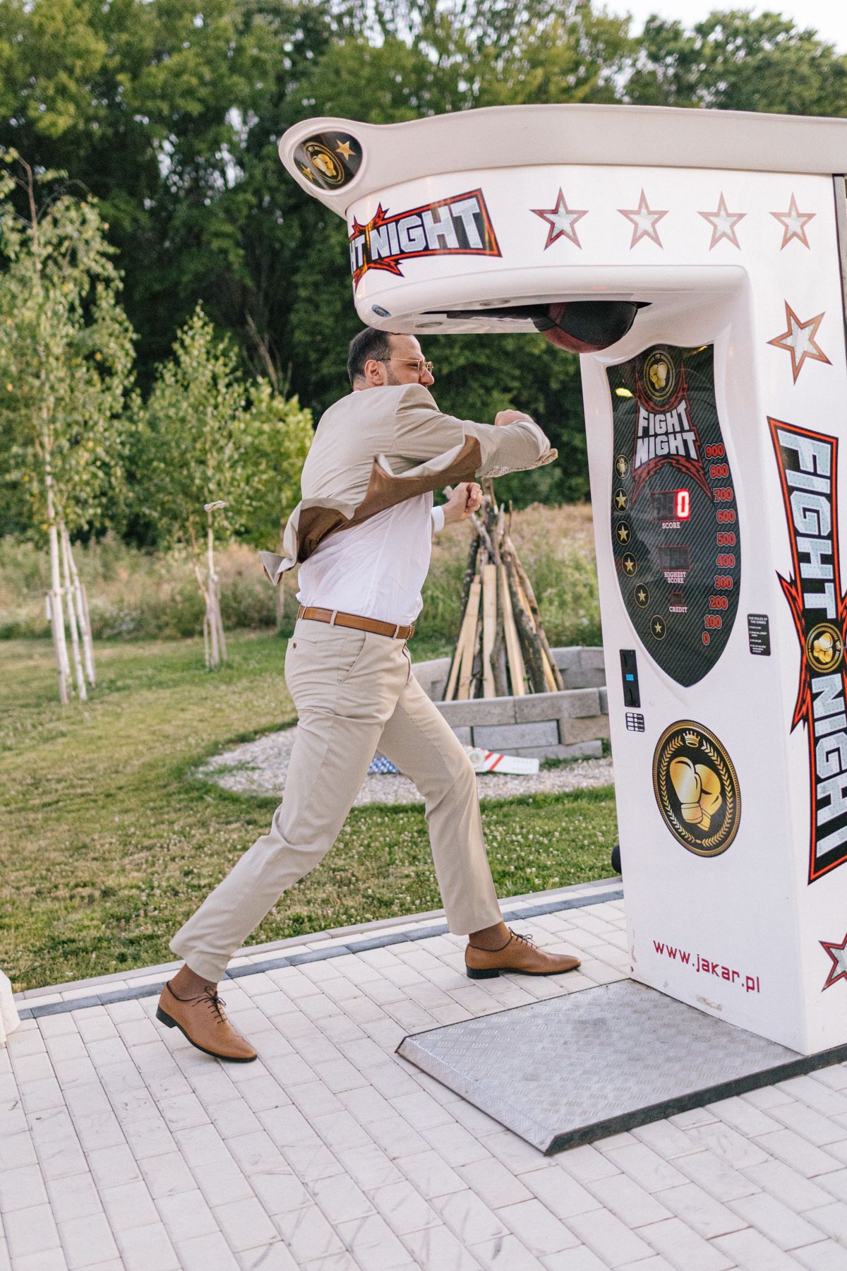Wedding guests play a competitive punching game at an outdoor reception entertainment station.