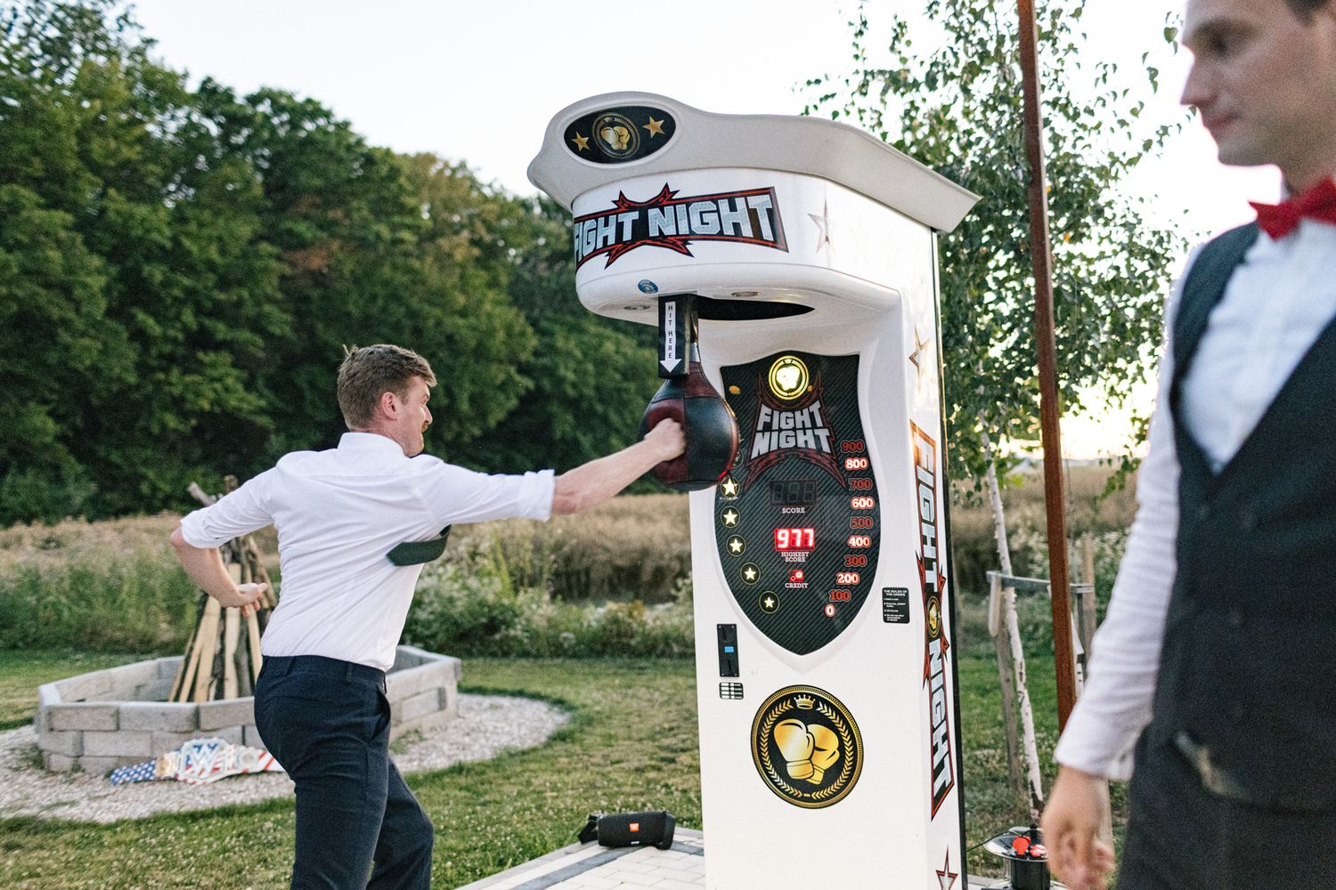Multiple guests take turns testing their strength on a carnival punching game at a wedding reception.