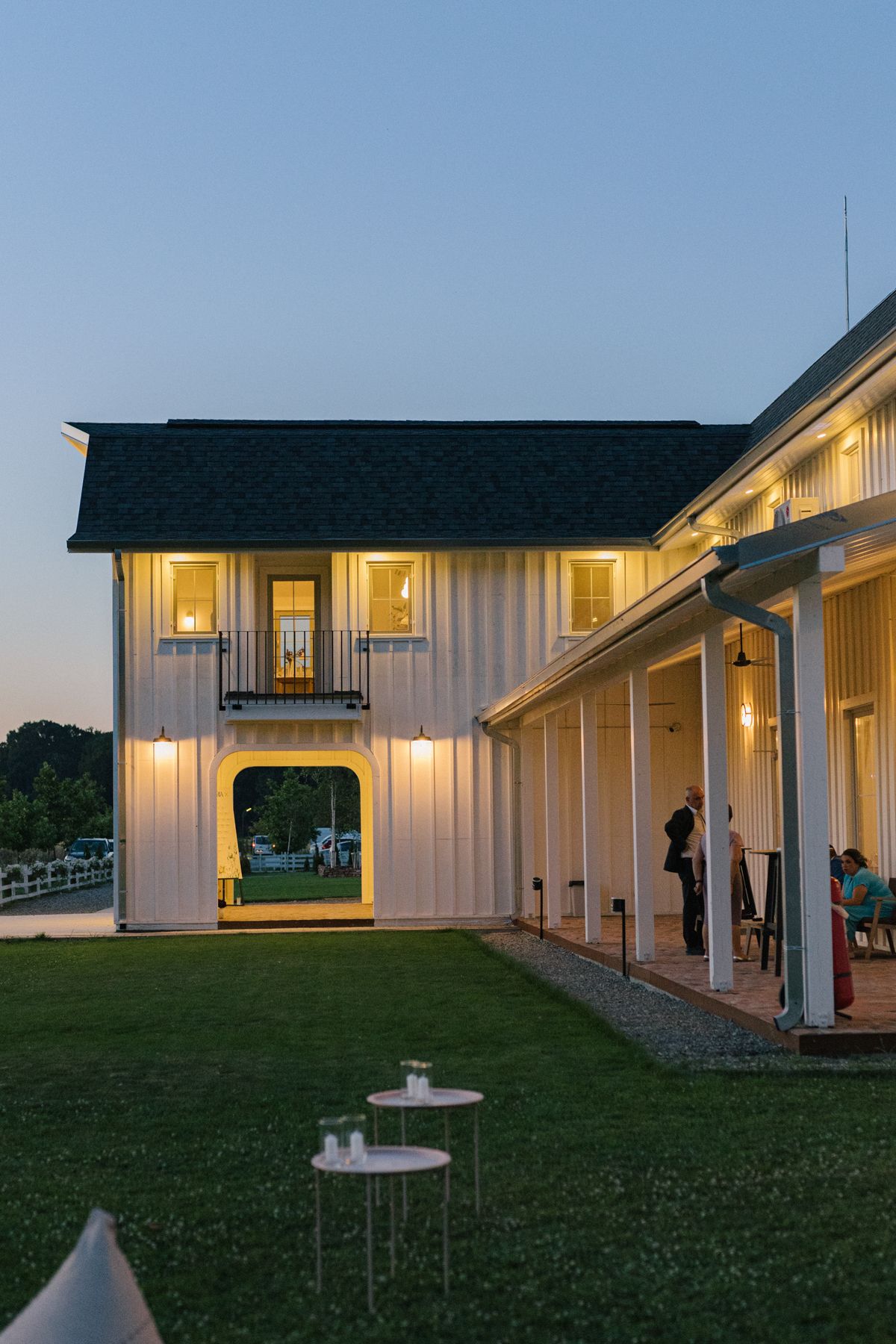 Elegant white barn wedding venue exterior shown at twilight with ambient lighting.