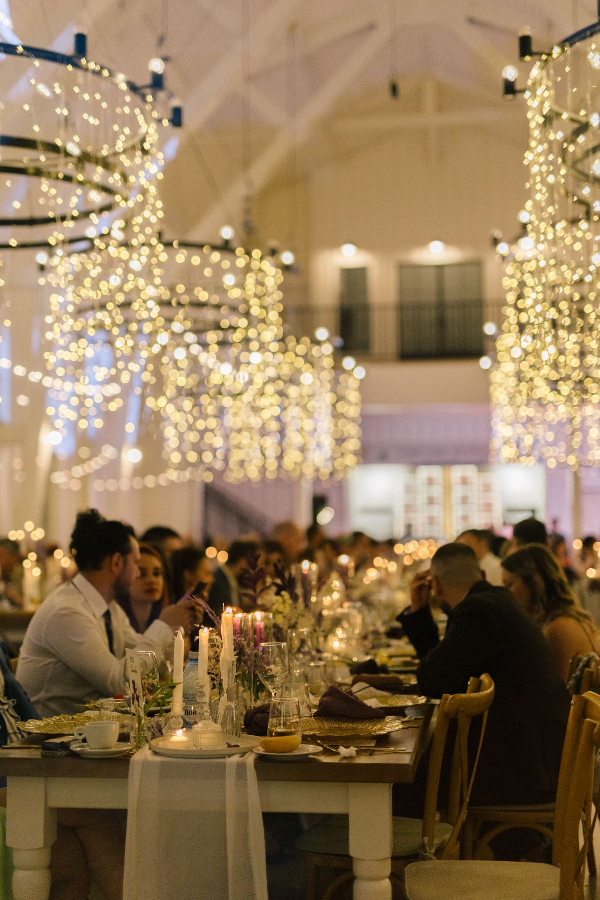 Elegant wedding reception venue with hanging string lights and tables set for dinner service.
