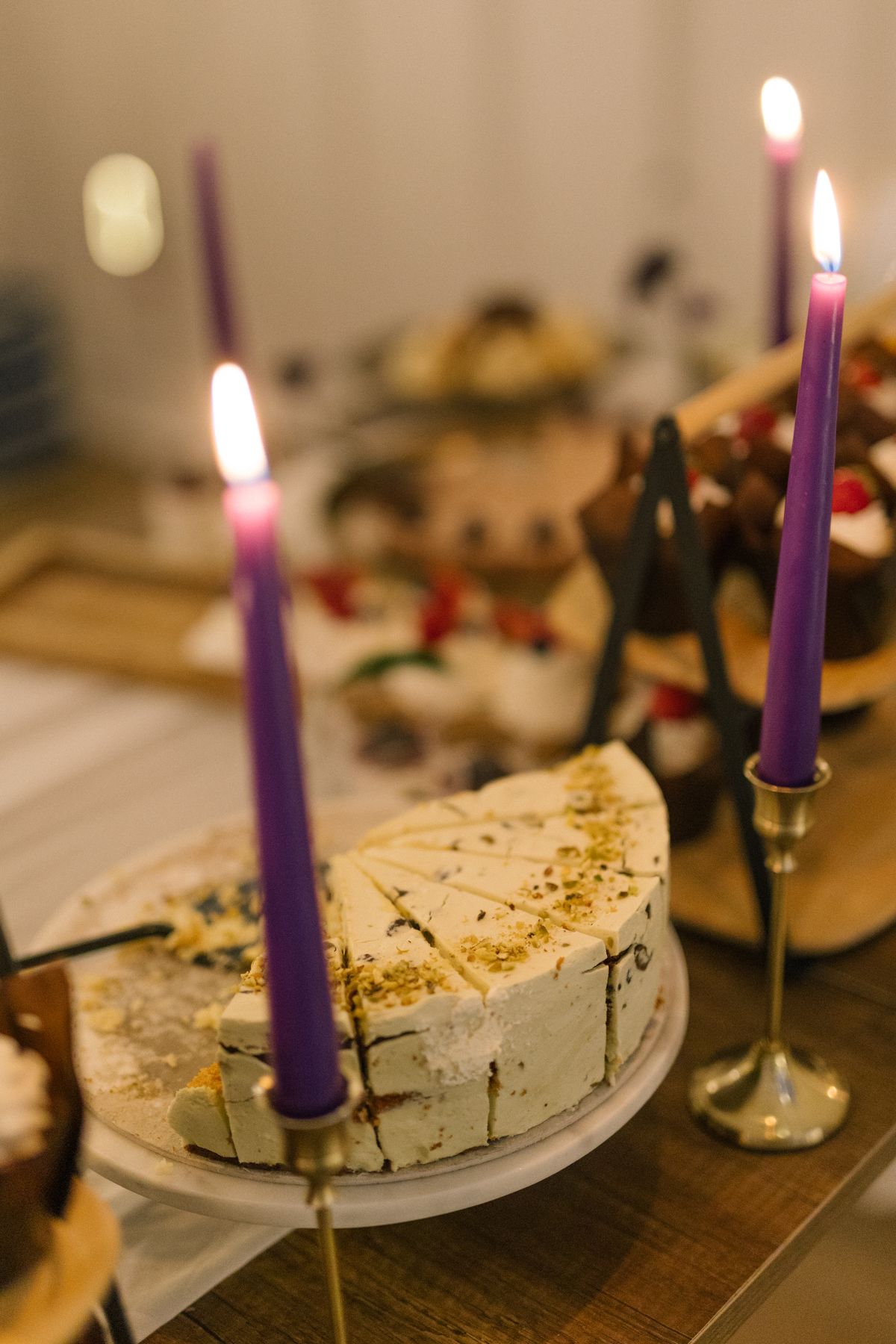 Purple candles and place settings on rustic wooden tables at an intimate dinner event.
